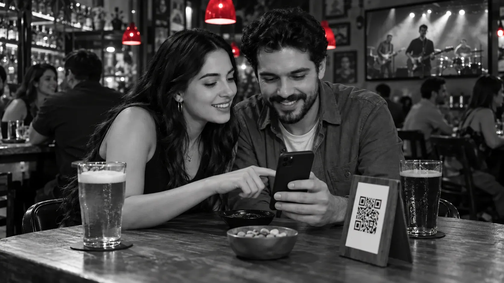 Dos clientes mirando un celular, con su parte trasera visible, junto a un QR de mesa en un bar